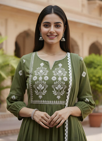 Woman wearing a green embroidered dress standing outdoors with architectural elements in the background