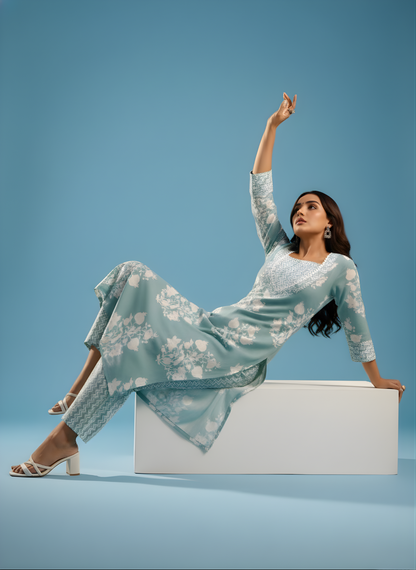 Woman in a light blue floral dress sitting on a white box against a blue background
