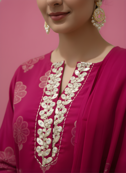 Close-up of a pink traditional outfit with intricate white embroidery on a pink background