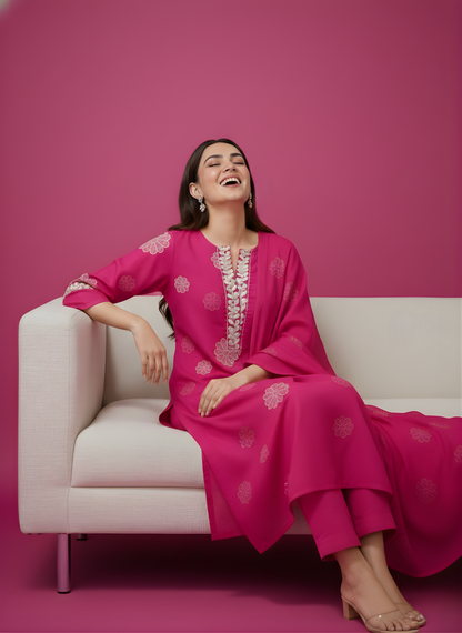 Woman in a pink traditional outfit sitting on a white couch against a pink background