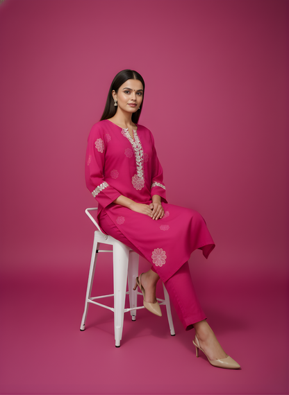 Woman in a pink outfit sitting on a white stool against a pink background