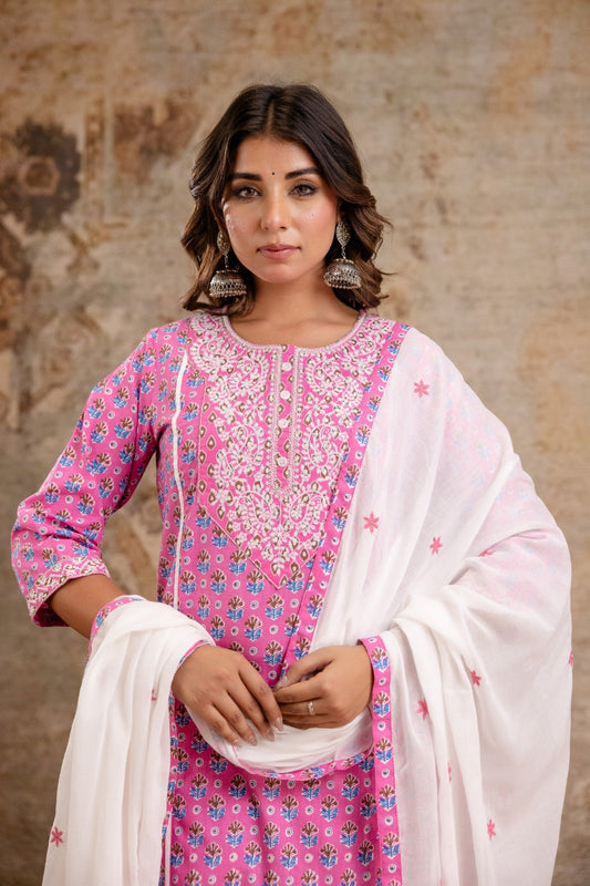 Woman wearing a pink and white traditional outfit with a textured wall background