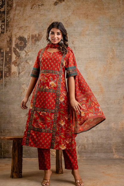 Woman wearing a red traditional outfit with floral patterns against a textured wall.
