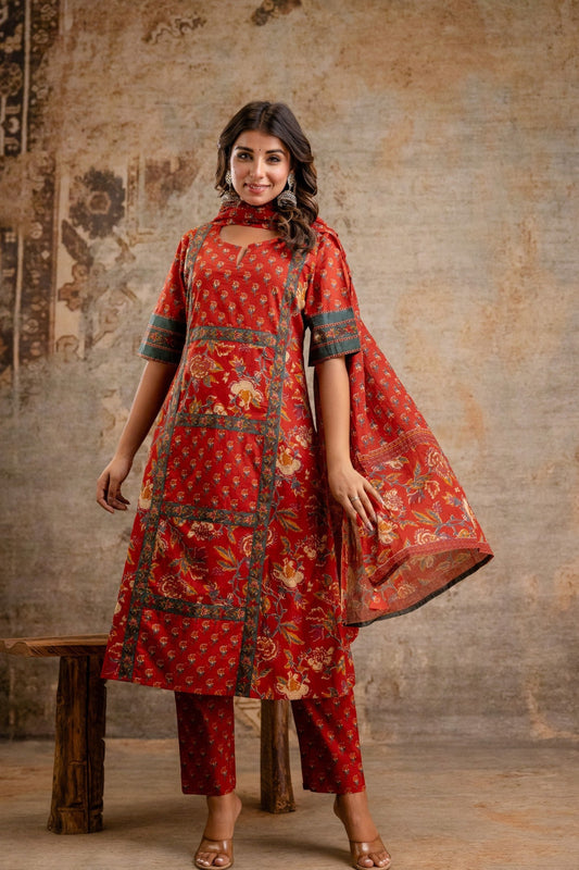 Woman wearing a red traditional outfit with floral patterns against a textured wall.