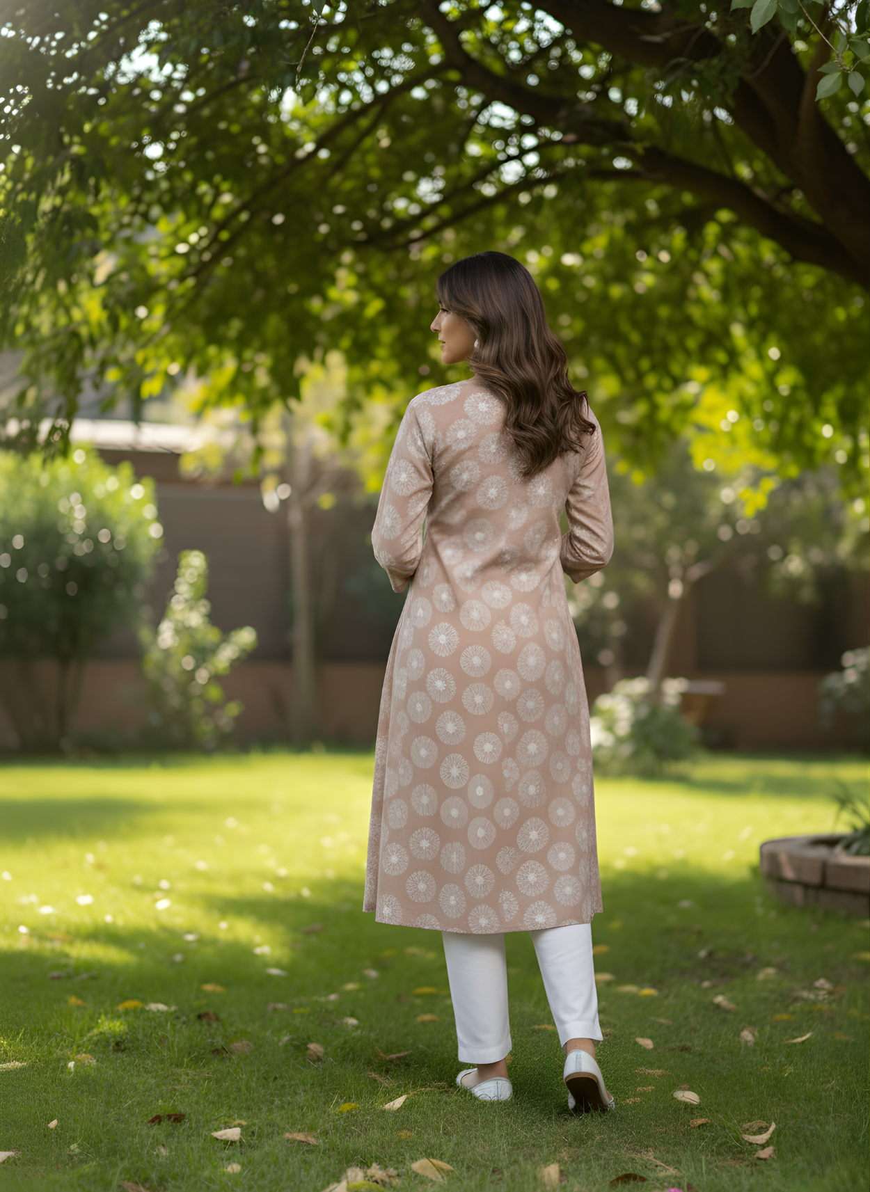 Woman in a beige patterned kurta standing in a garden