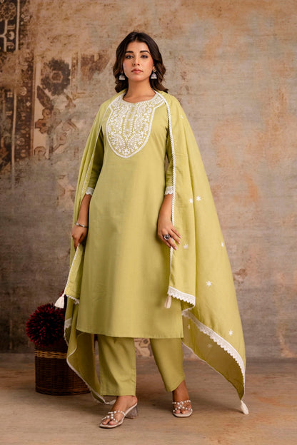 Woman wearing a light green traditional outfit with a textured wall background