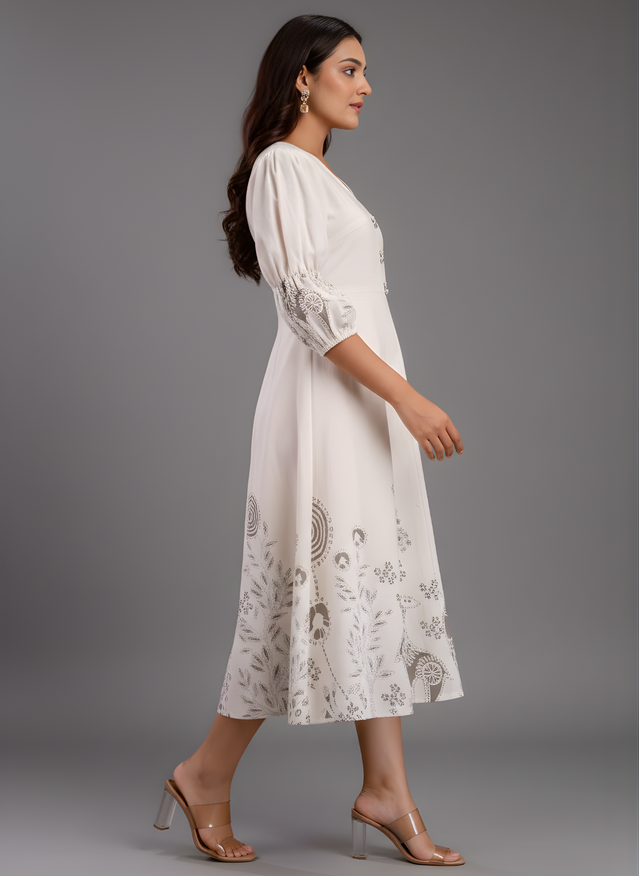 Woman wearing a white dress with intricate patterns on a gray background