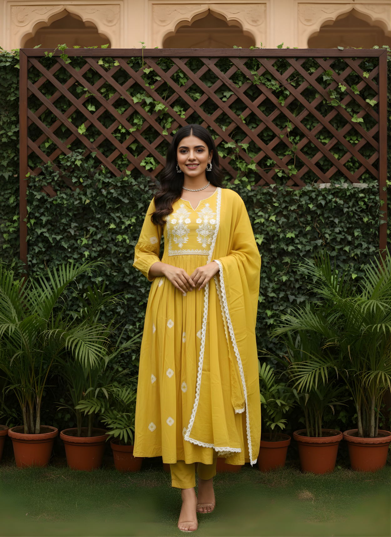 Woman in a yellow traditional outfit standing in front of a green leafy background