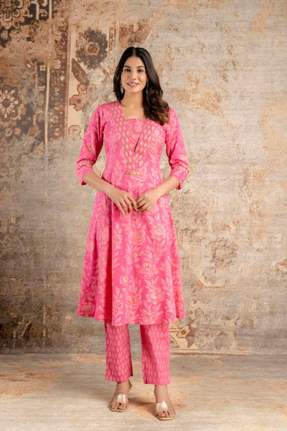 Woman wearing a pink traditional outfit against a textured wall.