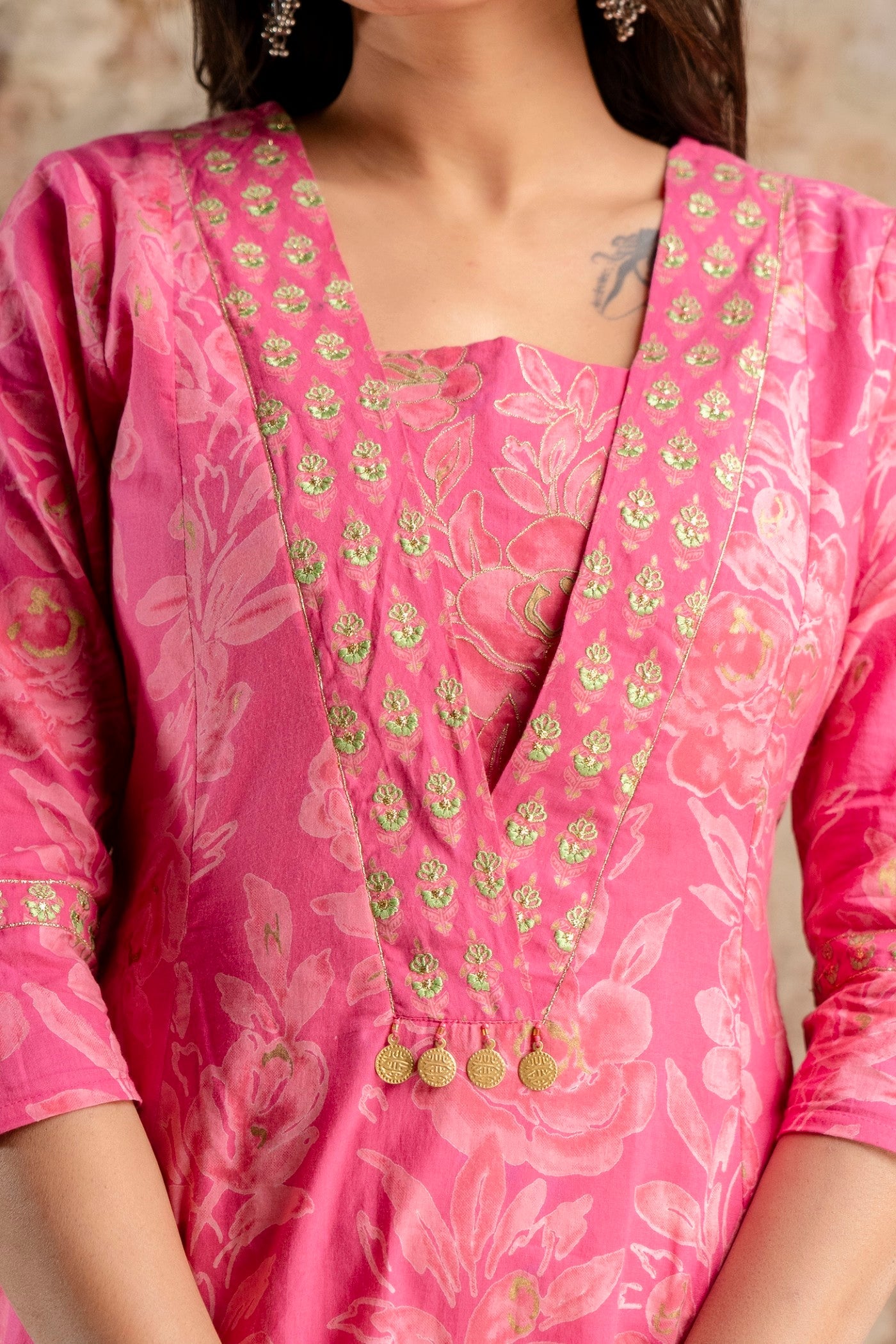 Close-up of a pink traditional outfit with floral patterns and gold accents.