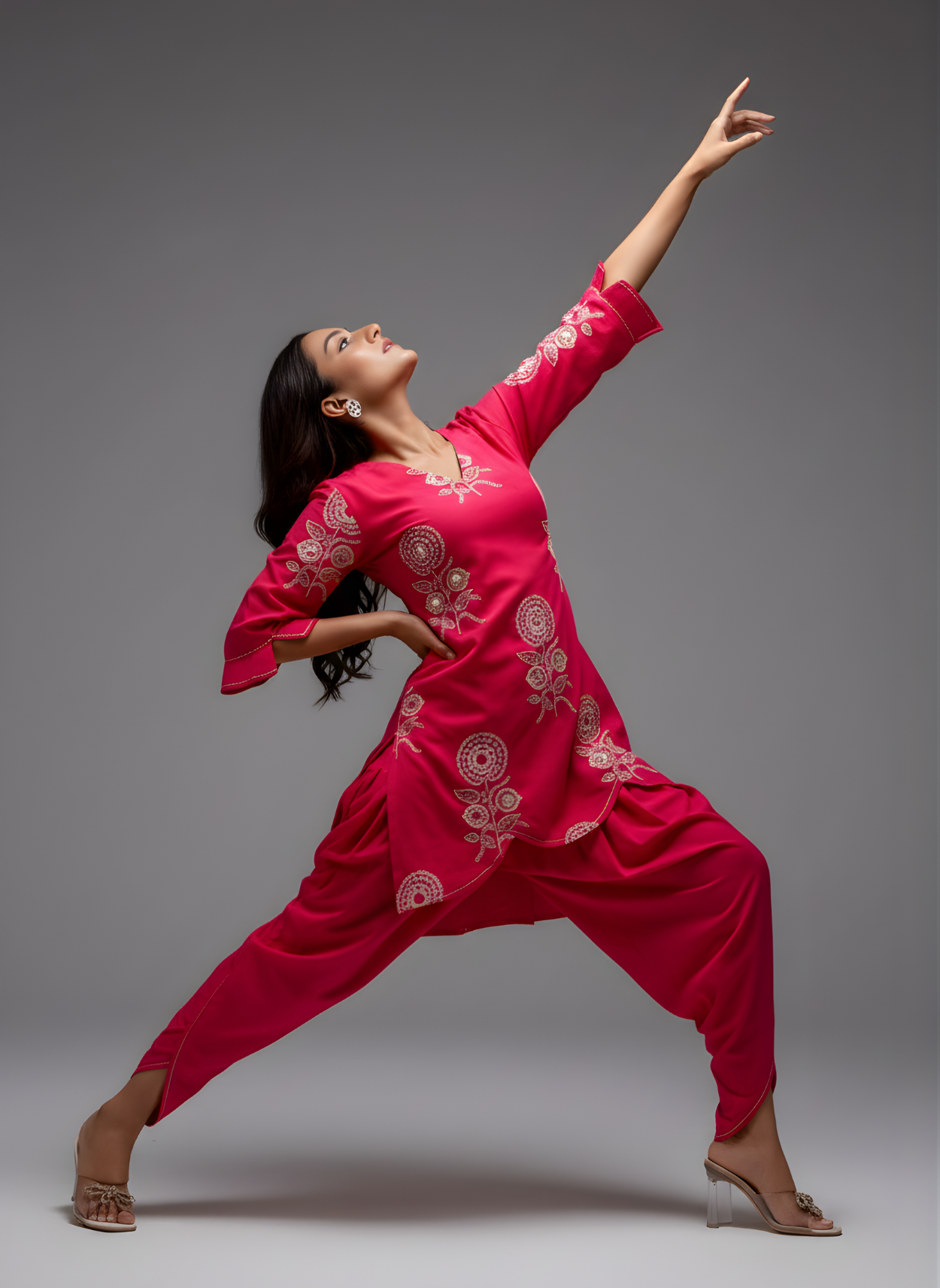 Dancer in a bright pink traditional outfit with white patterns on a gray background